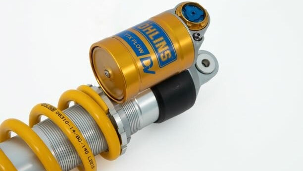 Close-up of a coilover suspension system with Ohlins branding on a white background